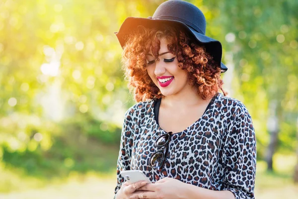 Moderna rossa giovane donna in parco in autunno con smart phone — Foto Stock