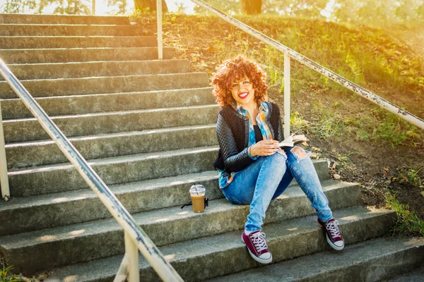 Menina adolescente legal lendo um livro ao ar livre sentado nas escadas — Fotografia de Stock