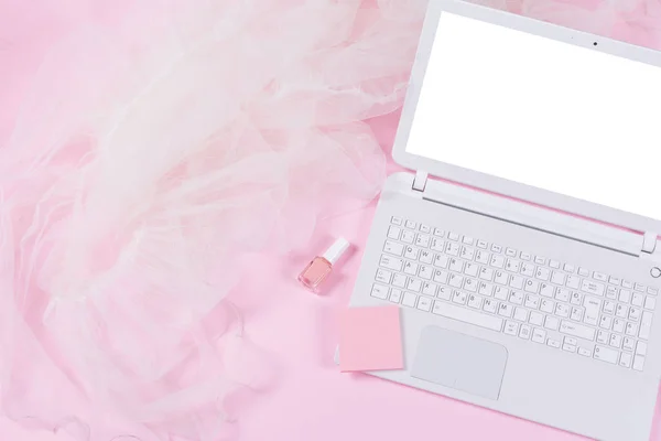 White laptop, notes, nail polish and tulle on pink background