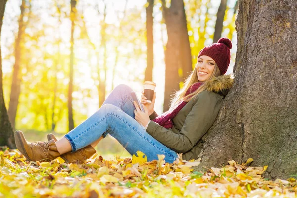 Giovane donna allegra in autunno nel parco con smart phone e caffè da asporto — Foto Stock