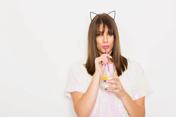 Jeune femme moderne buvant de l'alcool portant haut pailleté et oreilles de chat — Photo