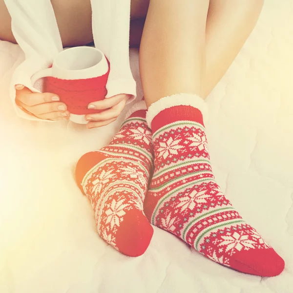 Jeune femme en chaussettes de Noël tenant une tasse avec du thé ou du café — Photo