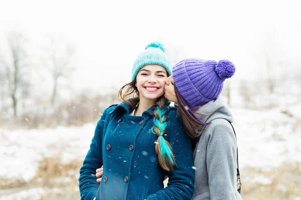 在下雪的冬日里 两个女朋友在户外拥抱和接吻 两位女性朋友在户外享受冬季旅行 — 图库照片