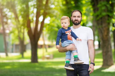 Yürümeye başlayan çocuk oğlu açık havada park güneşli bahar gününde holding. baba. Doğal aydınlatma, hayır rötuş, portre, canlı renkler