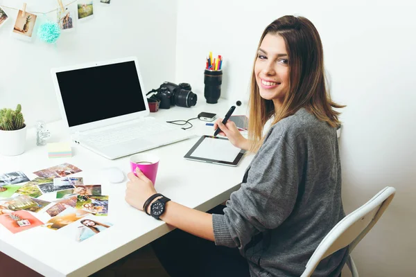 若いフリーランスの女性カメラマン 自宅のホーム オフィスのラップトップに取り組んで ロイヤリティフリーのストック写真