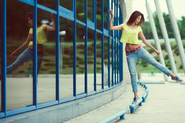 Улыбающаяся смешная хипстерша в синих джинсах танцует и балансирует — стоковое фото