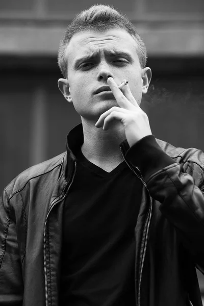 Bad boy concept. Portrait of brutal young man with short hair smoking — Stock Photo, Image