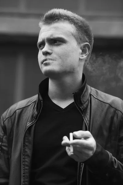 Bad boy concept. Portrait of brutal young man with short hair smoking — Stock Photo, Image