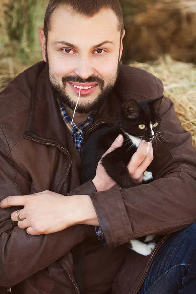 Ülke hayat kavramı. Genç gülümseyen bir kedi ile kahverengi deri ceketli adamı rahat — Stok fotoğraf