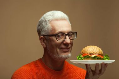 Her yaşta, vejetaryen gıda kavramı çok iyi. Olgun adam yeme hamburger portresi