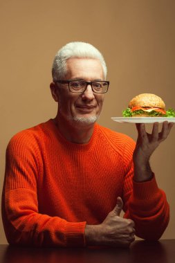 Sağlıksız yeme. Abur cubur kavramı. Burger ile mutlu olgun adam portresi