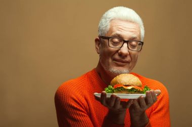 Her yaşta, vejetaryen gıda kavramı çok iyi. Burger ile mutlu olgun adam portresi