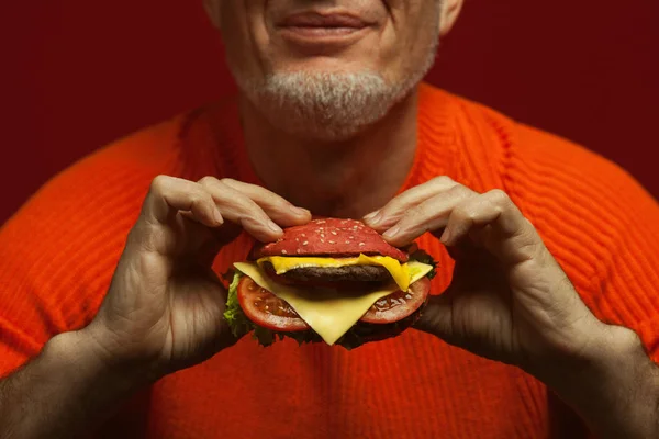 Comida pouco saudável. Conceito de comida de plástico. Retrato de homem maduro na moda comer hambúrguer — Fotografia de Stock