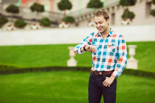 Retrato de jovem feliz posando perto de gramado verde no parque — Fotografia de Stock