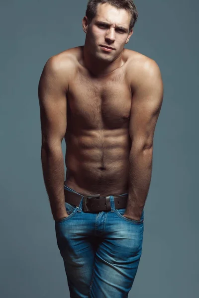 Красивая (красивая) мускулистая мужская модель с красивым прессом в синих джинсах — стоковое фото