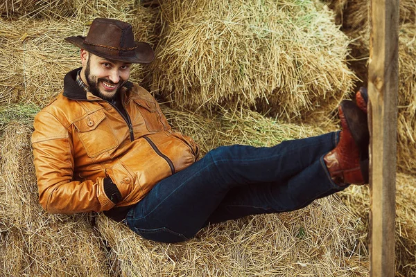 Wildwest-Konzept. Entspannter Cowboy in brauner Lederjacke lächelt — Stockfoto