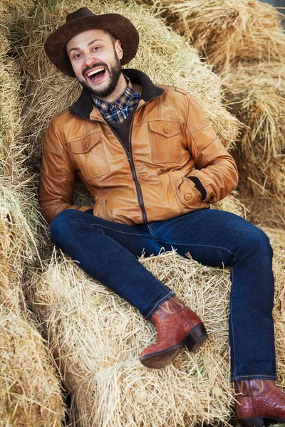 Conceito Wild West. Relaxado cowboy em jaqueta de couro marrom sorrindo — Fotografia de Stock