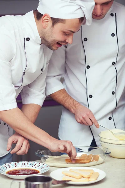 Tiramisu cooking concept. Portrait of two working men in cook uniform — Stock Photo, Image