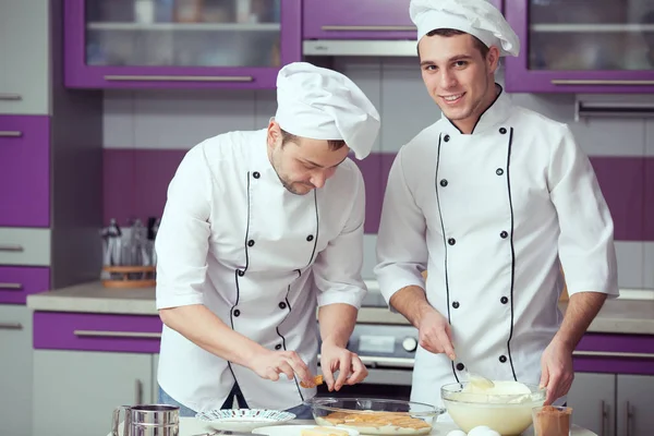Koncepcja gotowania tiramisu. Portret dwóch mężczyzn uśmiechający się w mundurze kucharz — Zdjęcie stockowe