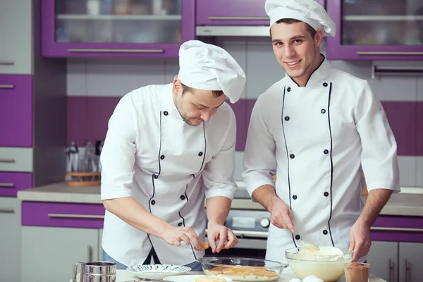 Tiramisu-Kochkonzept. Porträt zweier lächelnder Männer in Kochuniform — Stockfoto