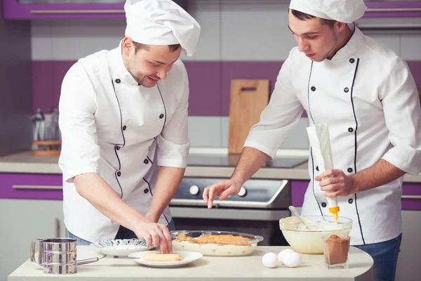 Koncepcja gotowania tiramisu. Portret dwóch mężczyzn uśmiechający się w mundurze kucharz — Zdjęcie stockowe