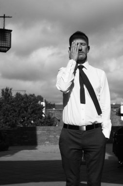 Smart casual yakışıklı olgun adam Avrupa şehri bina ve kameraya bakarak eski ev üzerinde duruyor. Yüzünde ver. Grafik gölgeler. Tek renkli açık vurdu