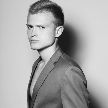 Erkekler moda kavramı. Muhteşem sarışın manken gri arka plan üzerinde poz gri ceketli portresi. Yakın çekim. Tek renkli stüdyo vurdu