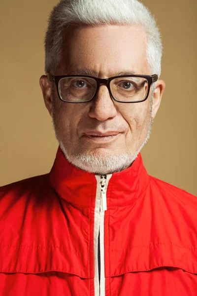 在任何年龄 眼镜的概念惊人 时尚60岁男子的肖像在红色夹克上米色 柔和的背景 时髦的发型 光泽的白发 关门了工作室拍摄 — 图库照片