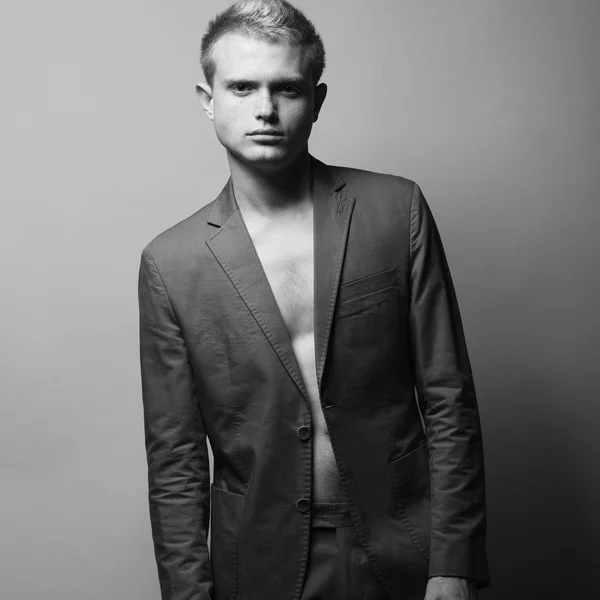 男性のファッションのコンセプトです 灰色の背景にポーズ灰色のジャケットのゴージャスな金髪ファッションモデルの肖像画 モノクロ スタジオ撮影 — ストック写真