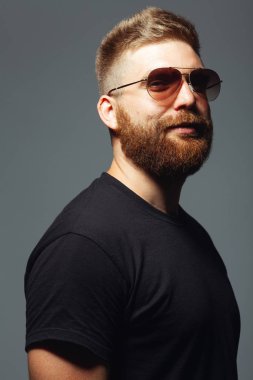 Göz giyimi konsepti. Her yaşta müthiştir. Koyu gri arka planda duran 30 yaşındaki kaslı adamın portresi. Mükemmel saç kesimi. Rock 'çı, motorcu, hipster tarzı. Stüdyo çekimi