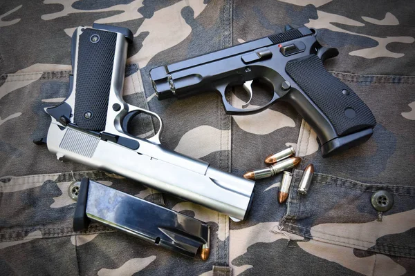 Twee semi-automatische pistolen en tas op camouflage soldaat pant — Stockfoto