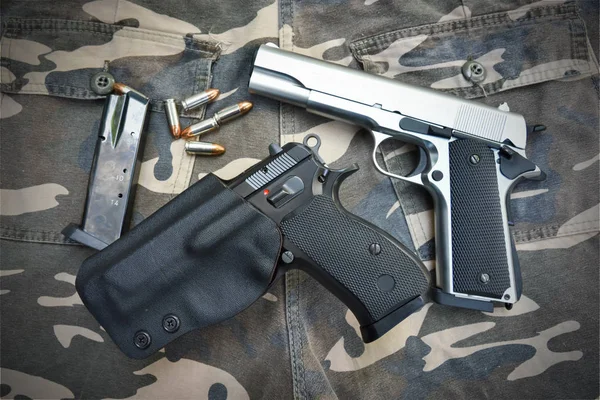 Dos pistolas semiautomáticas y bolso en pantalón de soldado de camuflaje — Foto de Stock