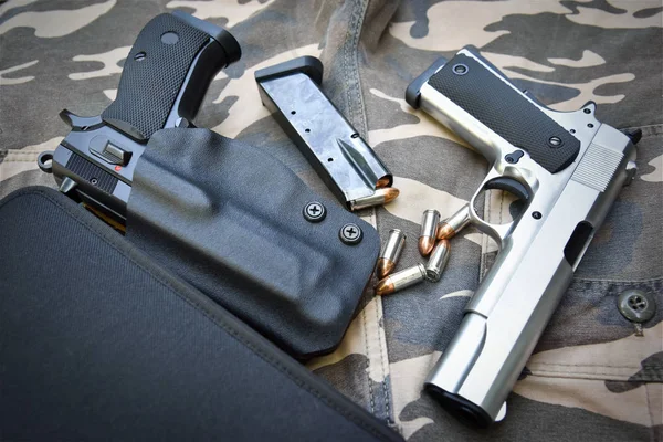 Due pistole semi-automatiche e borsa su pantalone militare mimetico — Foto Stock