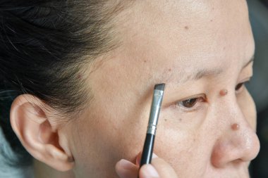  Asyalı kadın kaş fırçası ile makyaj uygulamak