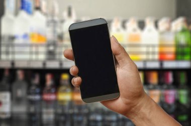 Smartphone şarap süpermarket mağaza üzerinde tutan bir el