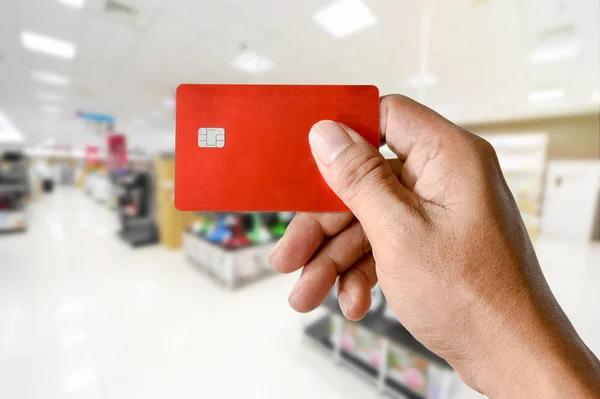 Eine Hand hält Kreditkarte auf verschwommenem Elektronikgeschäft — Stockfoto