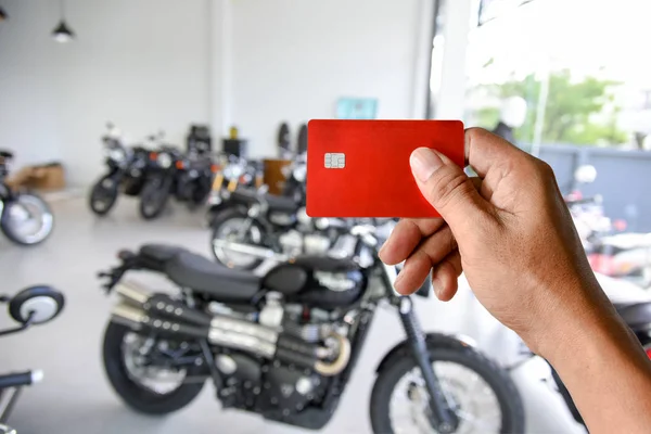 Uma mão segurando cartão de crédito no showroom da motocicleta — Fotografia de Stock