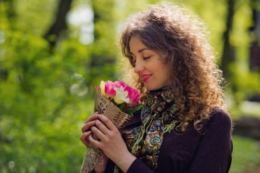 Bir buket çiçek ile bir parkta güzel kızıl saçlı kız.