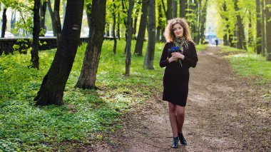 Bir buket çiçek ile bir parkta güzel kızıl saçlı kız.