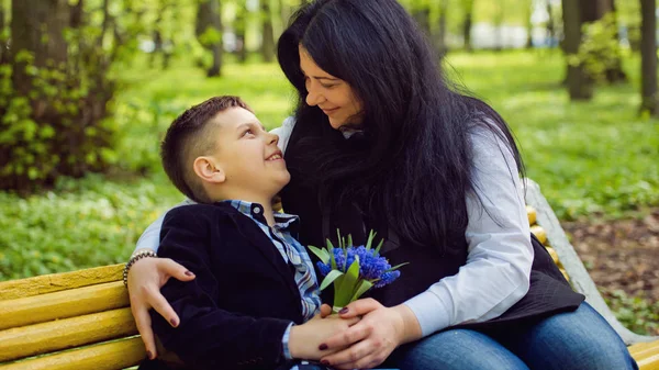 Сын подарил матери свежий букет синих цветов мускари на скамейке в парке . — стоковое фото