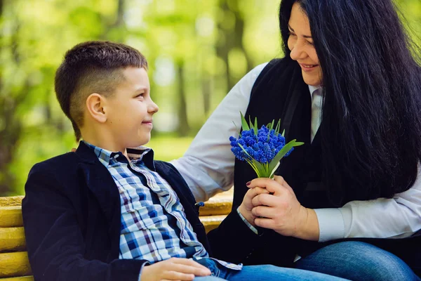 Сын подарил матери свежий букет синих цветов мускари на скамейке в парке . — стоковое фото