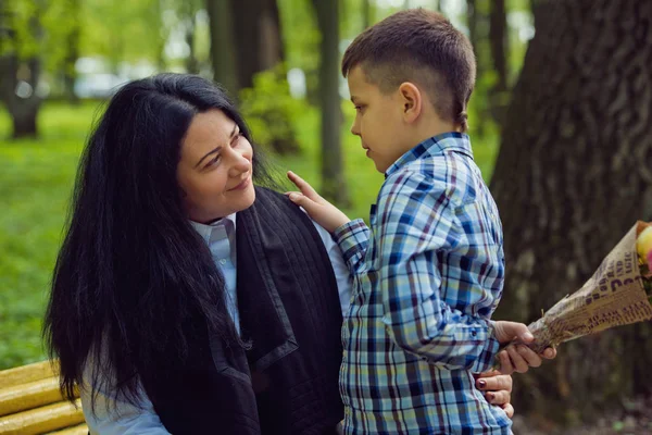 Le fils donne à sa mère un bouquet frais de fleurs de tulipes sur un banc dans le parc . — Photo