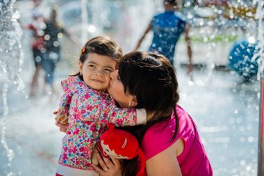 Küçük sevimli kız annesi çeşmenin parkta sarılmak. Anneler günü.