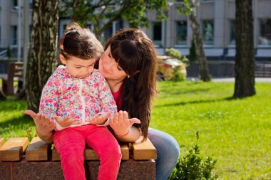 Anne ve kızı parkta bir bankta oturmuş ve onların palms adlı bakın. Anneler günü.