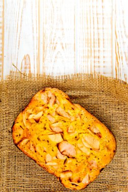 Taze ekmek. Beyaz ahşap zemin üzerinde çul üzerinde üstten görünüm pişmiş turta elmalı. Rustik tarzı.