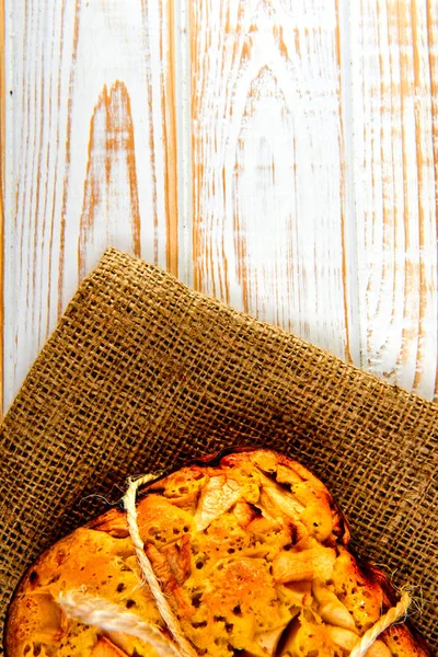 Taze ekmek. Beyaz ahşap zemin üzerinde çul üzerinde üstten görünüm pişmiş turta elmalı. Rustik tarzı.