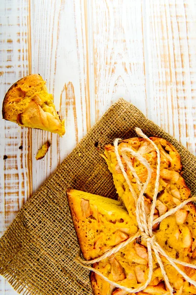 Taze ekmek. Beyaz ahşap zemin üzerinde çul üzerinde üstten görünüm pişmiş turta elmalı. Rustik tarzı.