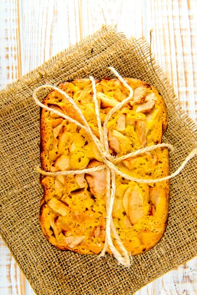 Taze ekmek. Beyaz ahşap zemin üzerinde çul üzerinde üstten görünüm pişmiş turta elmalı. Rustik tarzı.