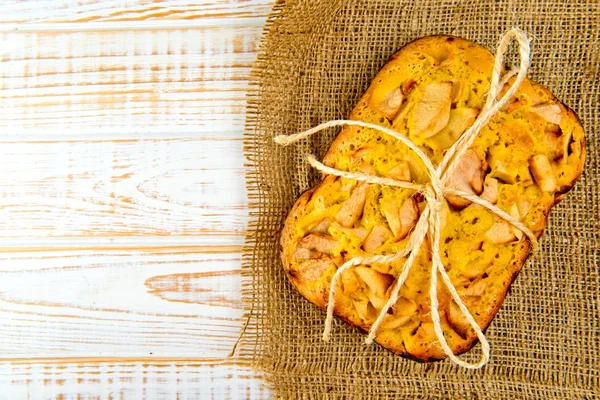 Taze ekmek. Beyaz ahşap zemin üzerinde çul üzerinde üstten görünüm pişmiş turta elmalı. Rustik tarzı.