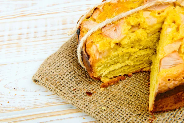 Taze ekmek. Beyaz ahşap zemin üzerinde çul üzerinde elma ile pişmiş pasta close-up. Rustik tarzı.